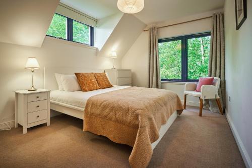 a bedroom with a bed and a chair and windows at Luxury Glenardle Lodge with Hot Tub and Forest Views in Bridge of Cally