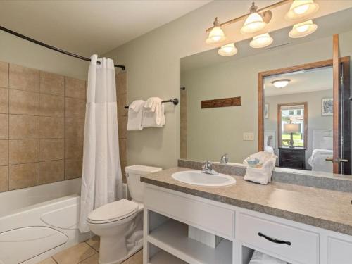 Un baño con inodoro, lavabo y espejo. en Bay Colony 762 - Lower, en Nisswa