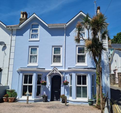 a blue house with a palm tree in front of it at The Melville in Brixham