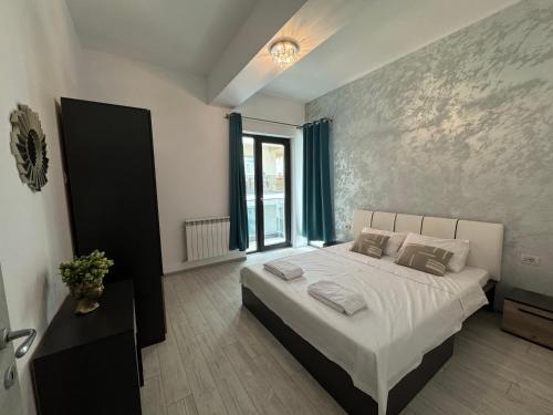 ein Schlafzimmer mit einem großen Bett mit weißen Laken und Kissen in der Unterkunft Blue Apartment in Năvodari