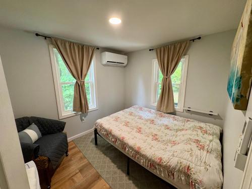 a bedroom with a bed and a couch and two windows at The Beach Gallery in Narragansett
