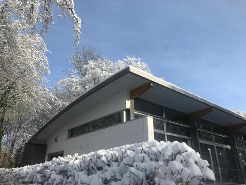 a building covered in snow with a pile of snow at La Maison d'Architecte en pleine nature - le "Clos des Chevreuils" in Barbençon
