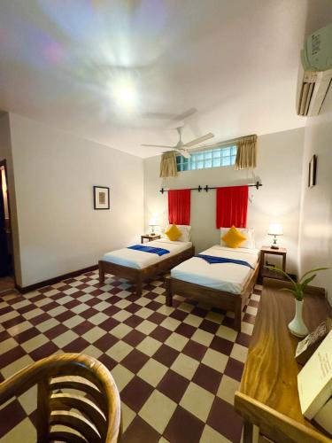 a bedroom with two beds and a checkered floor at Cozy Paradise in Battambang