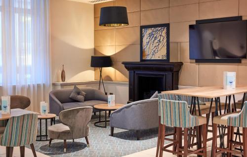 a hotel lobby with a fireplace and tables and chairs at Thistle London Holborn in London