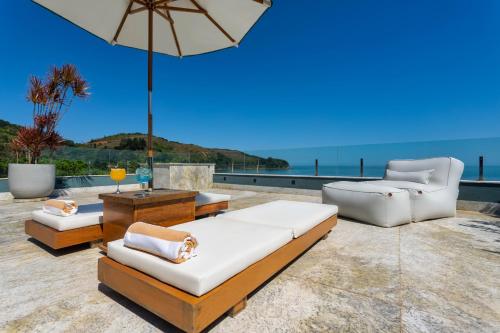 a patio with two couches and an umbrella at Duke Beach Hotel Maresias in Maresias