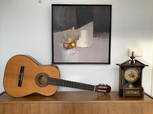 a guitar sitting on a shelf next to a clock at La Maison d'Architecte en pleine nature - le "Clos des Chevreuils" in Barbençon