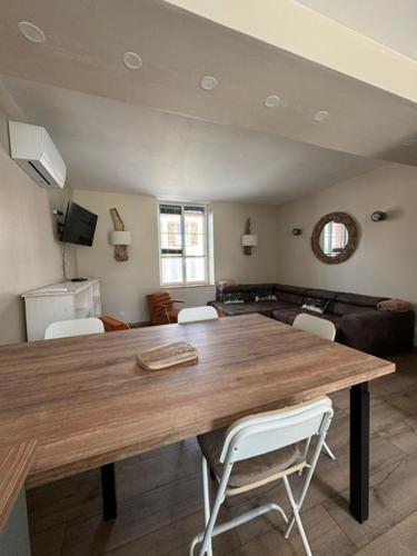 un salon avec une table en bois et des chaises blanches dans l'établissement La tanière des ours, à Chaumont-sur-Tharonne