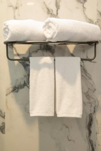 a group of white towels on a rack in a bathroom at Joon Canggu Apartment in Canggu