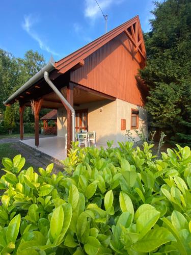 una casa con techo naranja y algunos arbustos verdes en Kemencés vendégház, en Balatonfenyves