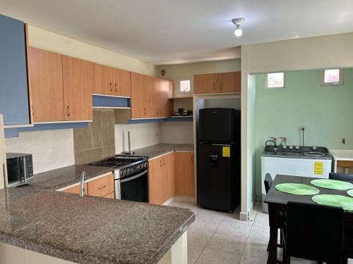 a kitchen with wooden cabinets and a black refrigerator at Casa en Urbanización La Arboleda Manta Manabí in Manta