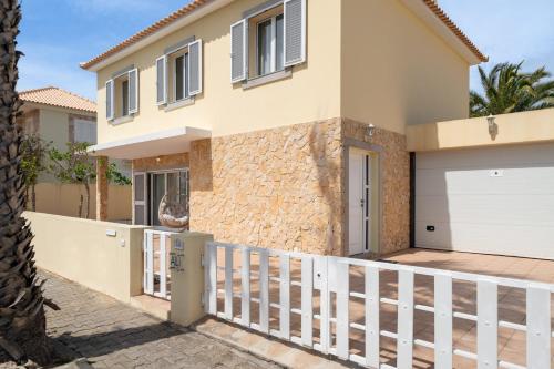 ein Haus mit einem weißen Zaun davor in der Unterkunft Moradia Felicidade Rocha PXO by An Island Apart in Porto Santo