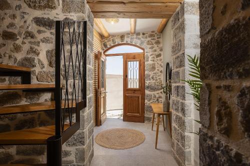 a hallway with a stone wall and a wooden door at Thèas House in Mírthios