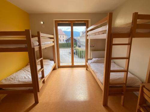 une chambre avec trois lits superposés et une fenêtre dans l'établissement Auberge de Jeunesse HI Pontarlier, à Pontarlier