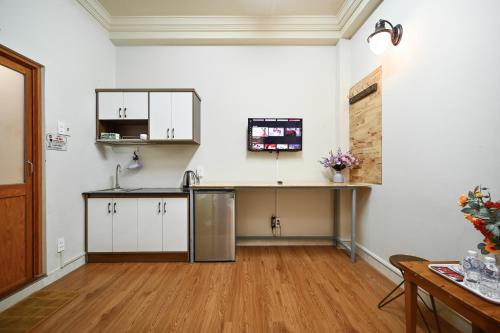 a kitchen with white cabinets and a wooden floor at A&E Guesthouse in Ho Chi Minh City