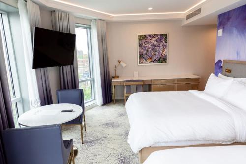 a hotel room with a bed and a desk and a tv at Iris Hotel Boston in Brookline