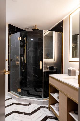 a bathroom with a shower with black tile at Iris Hotel Boston in Brookline