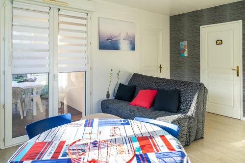 un salon avec un canapé et une table dans l'établissement Appartement avec jardin et plage, à Ouistreham