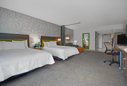 a hotel room with two beds and a television at Home2 Suites By Hilton Utica, Ny in Utica