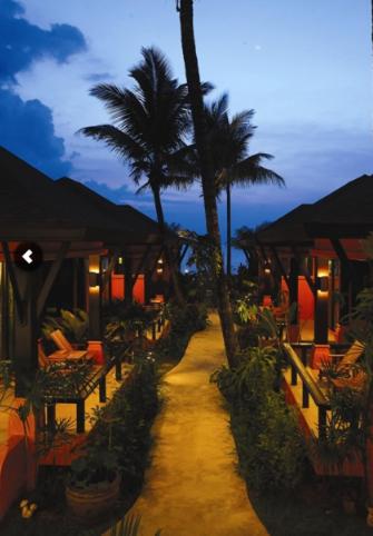 a pathway with chairs and palm trees in a resort at The Shambhala Khaolak Resort in Khao Lak