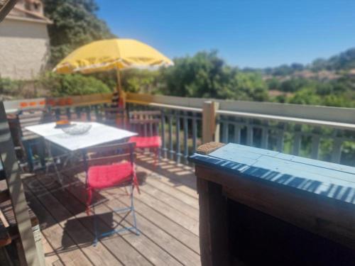 une table et des chaises sur une terrasse avec un parasol dans l'établissement Maison de village vençoise, à Vence