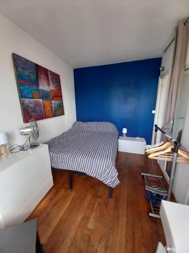 Cette chambre comprend un lit et un mur bleu. dans l'établissement Appartement Batignolles pour 2 pers, à Paris