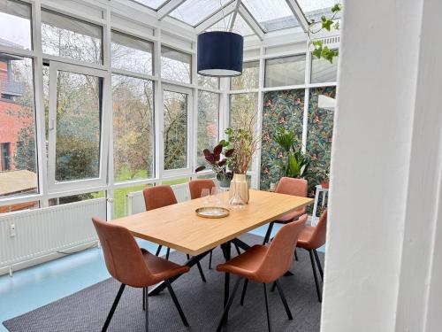 a dining room with a table and chairs and windows at Luxury 5BR City Villa - Chic & Spacious - Families in Oldenburg