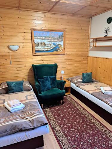 a room with two beds and a green chair at Penzion Havran in Ždiar