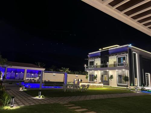 a house at night with blue lights on it at Calm Zone Luxury Private Pool 5BHK Villa in Al Ḩalāh