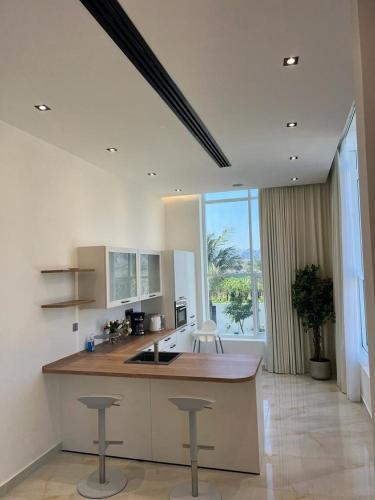 a kitchen with a counter and stools in a room at Calm Zone Luxury Private Pool 5BHK Villa in Al Ḩalāh