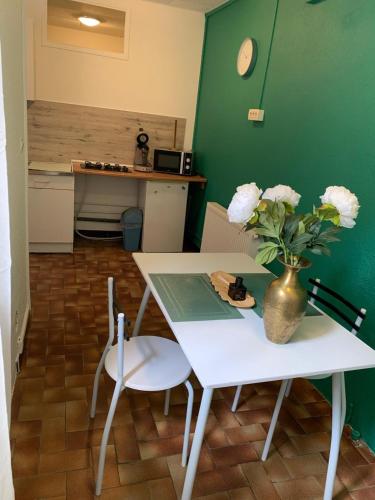 d'une table et de chaises avec un vase orné de fleurs. dans l'établissement Studio Carcassonne Hyper Centre, à Carcassonne