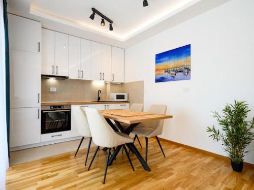 a kitchen with a wooden table and white cabinets at Apartman Adriatico 10 in Bar, Susanj