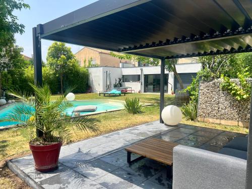 un patio avec une table en bois sous une pergola noire dans l'établissement Maison moderne Avignon pour 6 pers Piscine privée, à Avignon