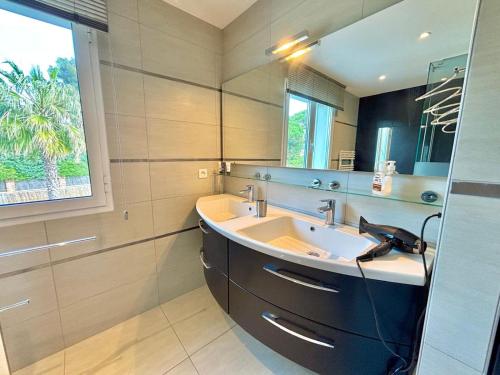 une salle de bain avec un lavabo et un grand miroir dans l'établissement Maison de Vacance La Belle, à Sainte-Maxime
