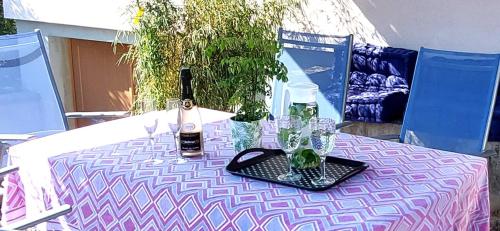 a pink and white table with bottles and glasses on it at Le gîte de Vitazensel in Logelbach