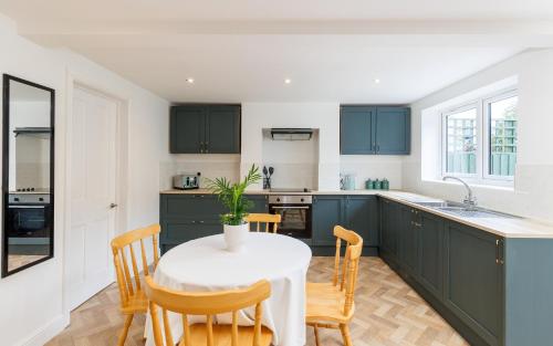 a kitchen with green cabinets and a table with chairs at Heart of Cowes - 10 Guests, 200m to Town, Sea View in Cowes