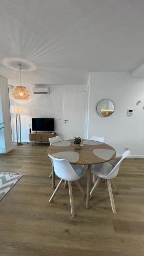 a dining room with a table and white chairs at Escale à Trafaria in Trafaria
