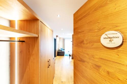 a sign on a wooden wall next to a door at Luxury Apartment Murmeltier mit 4-Sterne Hotelanbindung in Oberstaufen