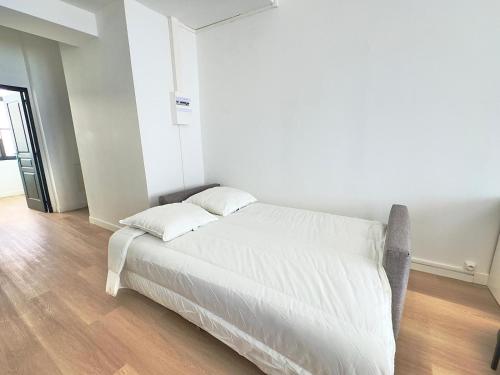 - un lit blanc dans une chambre blanche dotée de parquet dans l'établissement Cosy appart- 2 pers Netflix Hyper centre Douai, à Douai
