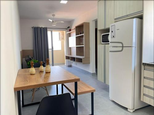 a kitchen with a dining table and a refrigerator at Bee Guest - Apartamentos de Temporada Luxxor Flat in Cuiabá