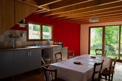 une cuisine avec une table et une cuisine aux murs rouges dans l'établissement Nuit *é* Toilée à la Ferme du Petit Puyaume, à Montravers