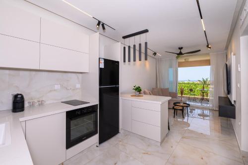 a kitchen with white cabinets and a black refrigerator at Royal Suite Caesarea in Caesarea