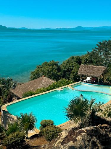 a swimming pool with the ocean in the background at Manja Kely Lodge in Nosy Be