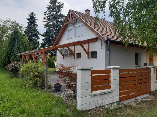 a small white house with a wooden fence at Nefelejcs-el vendeghaz in Balatonmáriafürdő