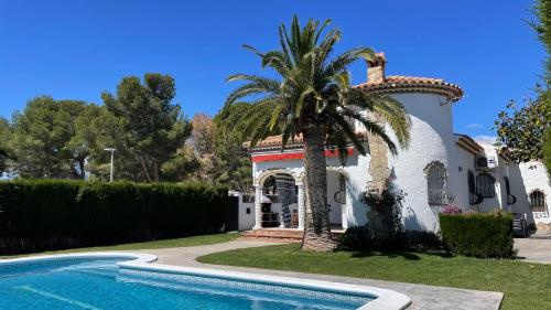 a villa with a palm tree next to a swimming pool at MEDDAYS Villa MARINA in Miami Platja