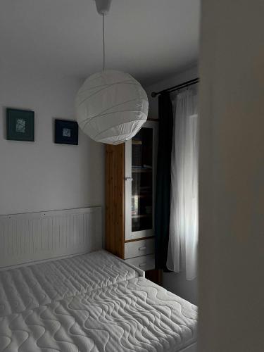 a bed in a bedroom with a large light fixture at Nefelejcs-el vendeghaz in Balatonmáriafürdő