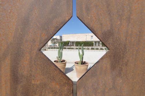 two potted plants are seen through a metal wall at Masseria Borgo Sentinella in Torre dell'Orso