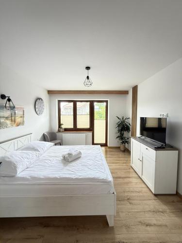 a white bedroom with a large bed and a kitchen at Apartamenty Wadowity- Energylandia Zator in Wadowice