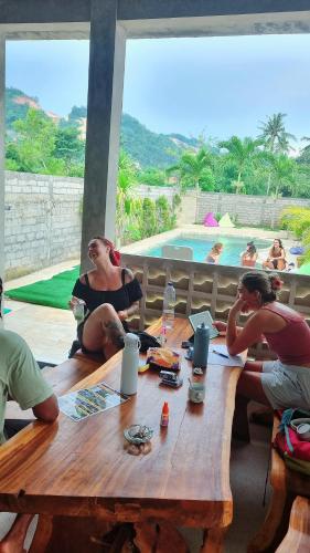 a group of people sitting around a wooden table at Jancoox Hostel in Kuta Lombok
