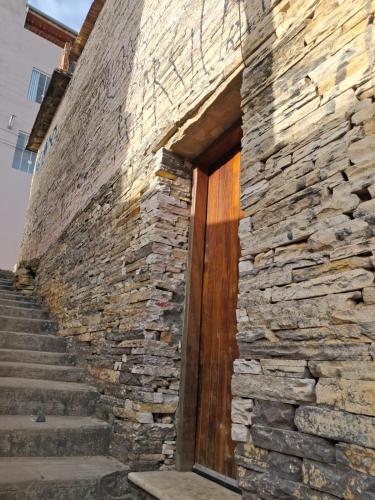 a stone building with a wooden door and stairs at Mahaidana Kitnet in São Thomé das Letras