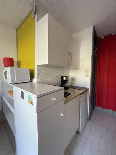 une petite cuisine avec des armoires blanches et un micro-ondes dans l'établissement Studio Port Nature PN54 - 2 personnes, au Cap d'Agde